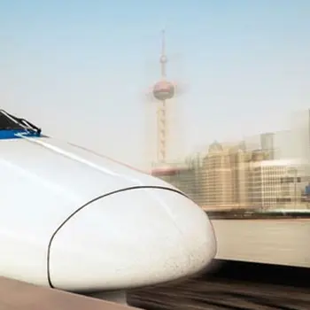 Weißer Hochgeschwindigkeitszug fährt vor Skyline aus dem Bahnhof, Symbol für Schmierung und Ölüberwachung bei modernen Schienenfahrzeugen
