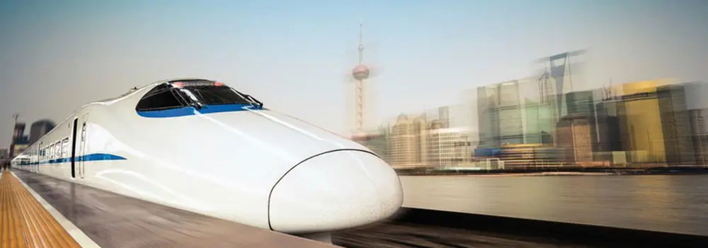 Schmierung und Ölüberwachung für Schienenfahrzeuge – Zuverlässigkeit im Hochgeschwindigkeitsverkehr Weißer Hochgeschwindigkeitszug fährt vor Skyline aus dem Bahnhof, Symbol für Schmierung und Ölüberwachung bei modernen Schienenfahrzeugen