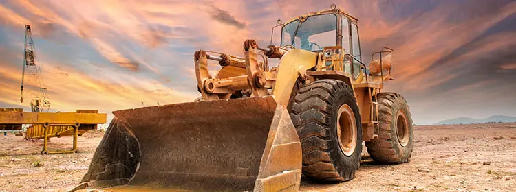 Schmierung und Ölüberwachung für Baumaschinen – Radlader & Co. zuverlässig im Einsatz halten Großer Radlader auf staubiger Baustelle bei Sonnenuntergang als Beispiel für stark beanspruchte Baumaschinen