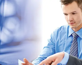 Zwei Fachleute im Gespräch über Unterlagen, links im Bild wird Motoröl aus einem Kanister gegossen – Symbol für ein Seminar zu Grundlagen der Schmierung