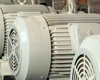 Mehrere graue Industriekompressoren bzw. Motor-Aggregate in einer Reihe in einer Anlagehalle