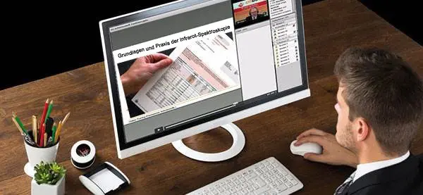 Grundlagen und Praxis der Infrarot-Spektroskopie – Online-Training Mann am Schreibtisch verfolgt ein Webinar zur „Grundlagen und Praxis der Infrarot-Spektroskopie“ auf einem großen Monitor
