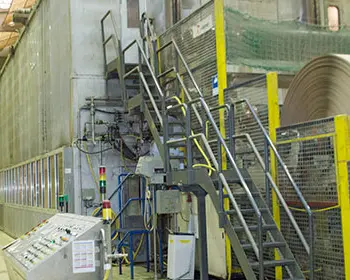 Produktionshalle mit großer Papiermaschine und aufgewickelter Papierrolle in einer Papierfabrik