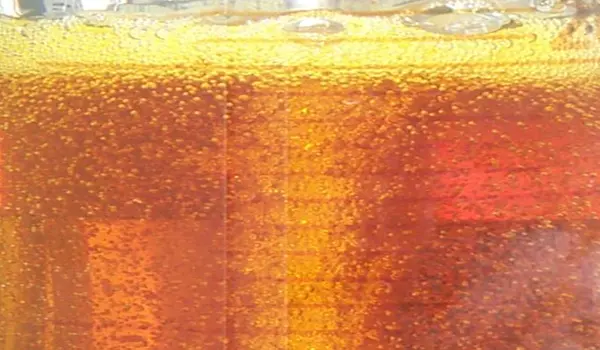 Nahaufnahme einer bernsteinfarbenen Ölprobe mit vielen kleinen Gas- oder Wasserbläschen