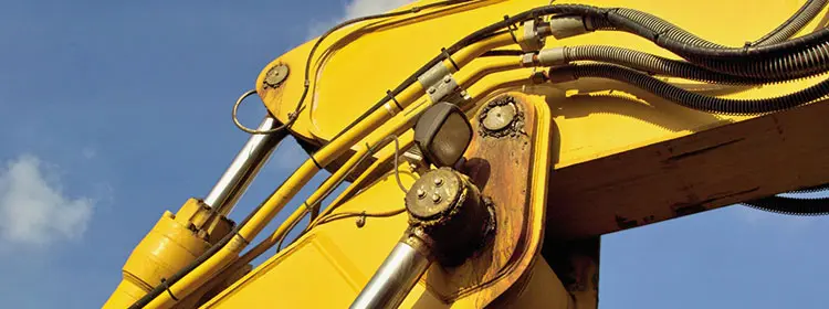 Hydrauliken richtig schmieren – Hydraulikzylinder, Leitungen und Gelenke zuverlässig schützen Gelber Baggerarm mit Hydraulikzylindern, Leitungen und Schmierstellen als Beispiel für richtig geschmierte Hydrauliken